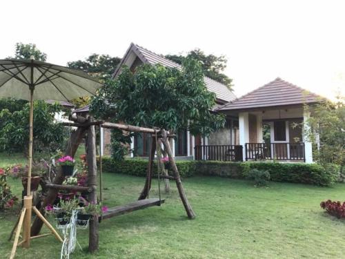 a playground in front of a house with an umbrella at Papai Country Lodge SHA in Ban Mae Pong