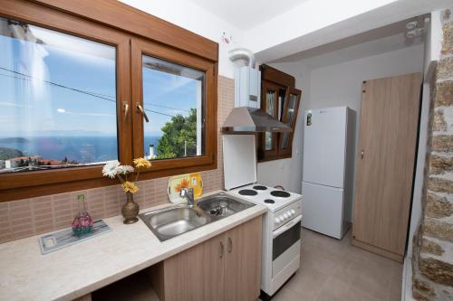 a kitchen with a sink and a white refrigerator at Casa di levante - Glossa Skopelos in Loutraki