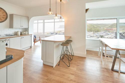 a kitchen with white cabinets and a table with stools at Host & Stay - Burnsyde Beach House in Saltburn-by-the-Sea