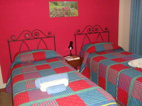 two beds in a room with red walls at Bed & Breakfast Barba Bertu in Frassino