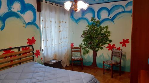 een slaapkamer met een bed en 2 stoelen en een boom bij Colori nel parco in Cesiomaggiore