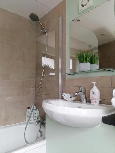 a bathroom with a sink and a mirror and a tub at Tynant House- Modern 3 bed house- City centre and FREE parking in Cardiff