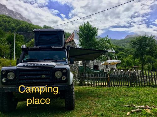 a truck parked in the grass with a camping place sign at Guest House Rrashkadoli in Theth