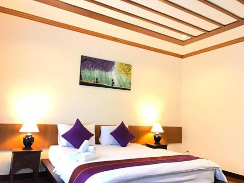a bedroom with a bed with purple pillows at Papai Country Lodge SHA in Ban Mae Pong