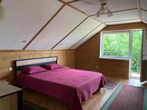 sypialnia z fioletowym łóżkiem na poddaszu w obiekcie Садиба Краєвид w mieście Polyana (Polana)