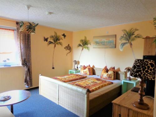 a bedroom with a bed with palm trees on the wall at Pension Sonnenhügel in Markersdorf