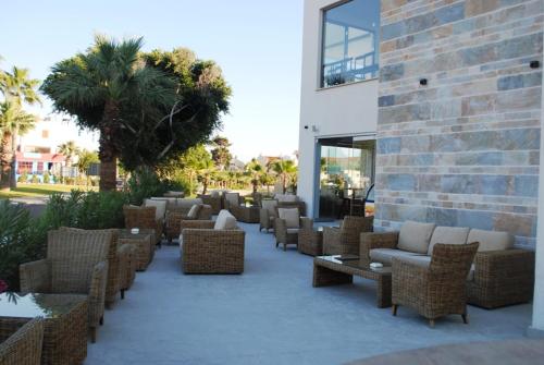 a patio with wicker chairs and tables next to a building at Gold Lagoon Kosher Hotel - by Amphora Hotel & Suites in Paphos City