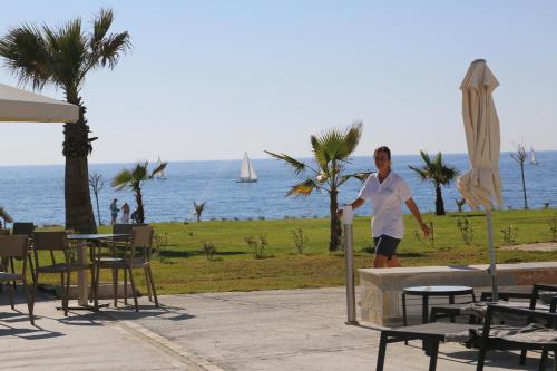 a man standing next to a fountain near the ocean at Gold Lagoon Kosher Hotel - by Amphora Hotel & Suites in Paphos City