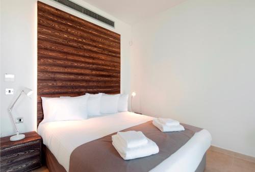 a bedroom with a large white bed with a wooden headboard at Gold Lagoon Kosher Hotel - by Amphora Hotel & Suites in Paphos City