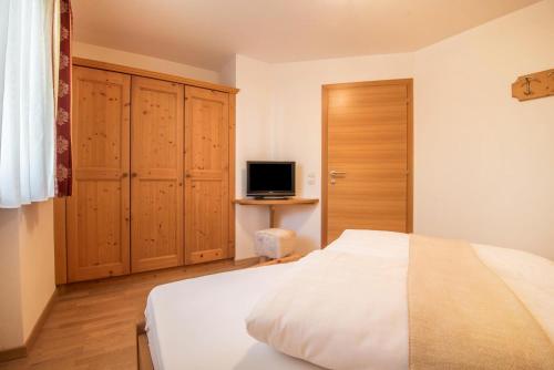 a bedroom with a bed and a television in it at Kristiania Apartement Typ A1 in Siusi