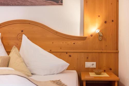 a bedroom with a bed with a wooden headboard at Kristiania Apartement Typ A1 in Siusi