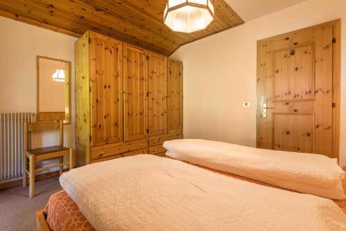 2 letti in una camera da letto con armadi in legno e una sedia di Casa Lorenz 4 a Canazei
