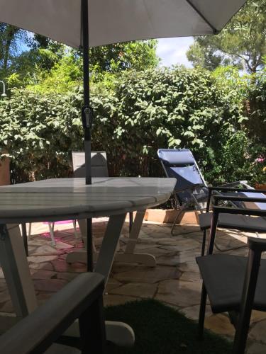 une table et des chaises avec un parasol et un ordinateur portable dans l'établissement Plage des Salins Parc des Salins St Tropez, à Saint-Tropez