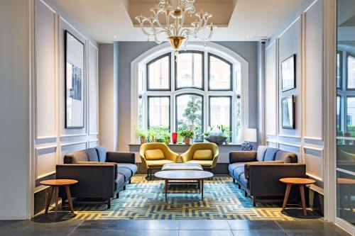 a living room with couches and tables and a chandelier at Radisson Blu Edwardian Bloomsbury Street Hotel, London in London