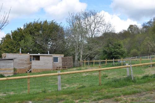 a wooden cabin in a field with a fence at Cosy and rural Lodge at Goldhill Glamping in Shaftesbury