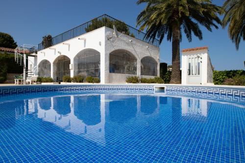 a swimming pool in front of a house with a palm tree at SANTA MONICA - ENERGiA MEDITERRANEA in Tossa de Mar