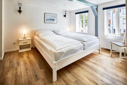een witte slaapkamer met een bed en een tafel bij fewo1846 - Hafen-Butze - komfortable Wohnung in historischem Gebäude im Stadtzentrum in Flensburg