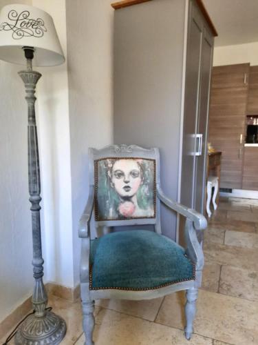 a chair with a portrait on it next to a lamp at Un Coin De Luberon in L'Isle-sur-la-Sorgue