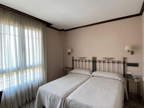a bedroom with a bed and a large window at Hotel Los Molinos in Llanes