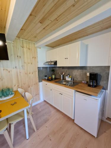 a kitchen with white cabinets and a table and a counter at Chalet Mugure de Brad in Fundu Moldovei