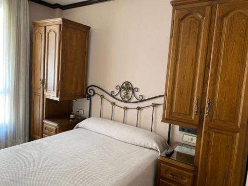 a bedroom with a white bed and wooden cabinets at Hotel Los Molinos in Llanes