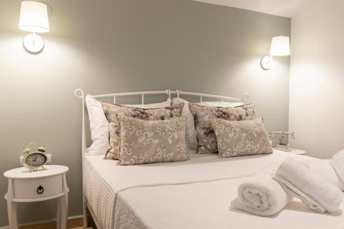 a bedroom with a white bed with pillows and a clock at Villa La Varik 2 in Litochoro