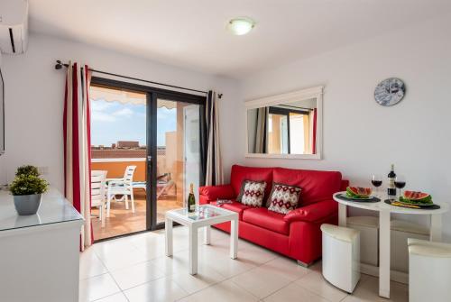 a living room with a red couch and a table at Tenerife South Apartments in Playa de las Americas