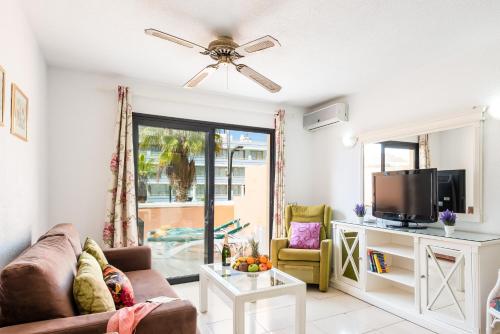 a living room with a couch and a tv at Tenerife South Apartments in Playa de las Americas