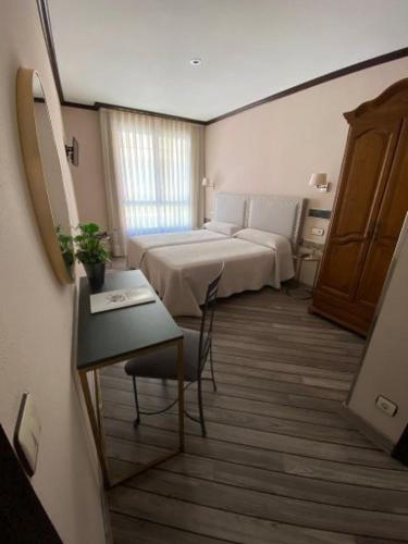 a room with two beds and a table with a desk at Hotel Los Molinos in Llanes