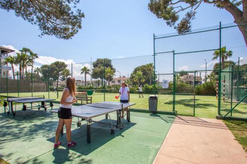 two women playing tennis on a tennis court at Playa Esperanza Resort Affiliated by Meliá in Playa de Muro