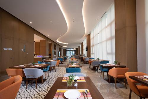 a dining room with tables and chairs and windows at Holiday Inn Express Chengdu Longquanyi North by IHG in Chengdu