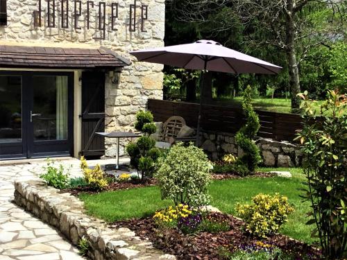 - un jardin avec un banc et un parasol dans l'établissement Auberge de la Sagne, à Cabrerets