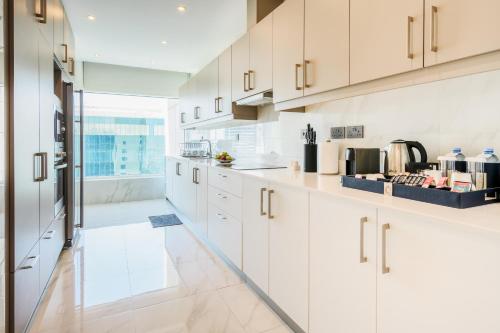 a kitchen with white cabinets and a large window at Centara West Bay Hotel & Residences Doha in Doha