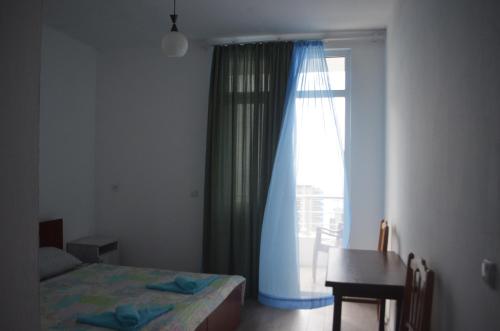 a bedroom with a bed and a window with a desk at Akhmed Guest House in Kvariati