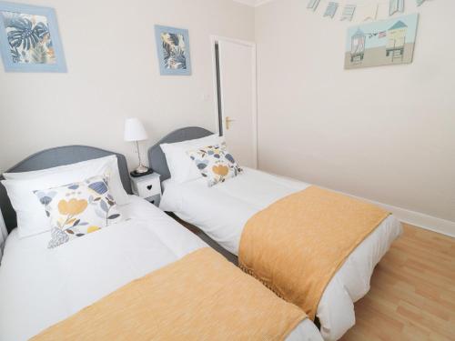 two beds in a room with white walls at Sandy Toes Cottage in Newbiggin-by-the-Sea