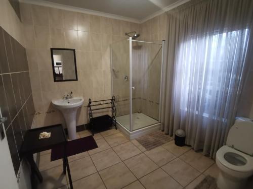 een badkamer met een douche, een wastafel en een toilet bij Harties 2 Sleeper Double Room with Private Bathroom in Hartbeespoort