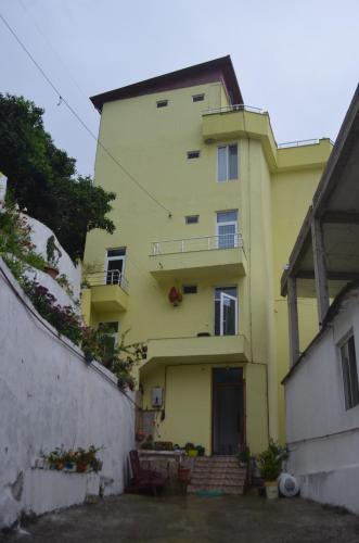 a yellow building with a balcony in a yard at Akhmed Guest House in Kvariati