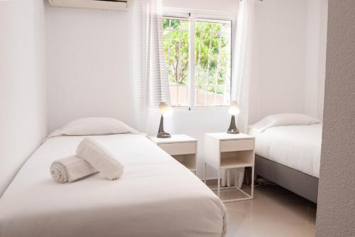 een witte slaapkamer met 2 bedden en een raam bij Myflats Premium Mirador in Arenales del Sol