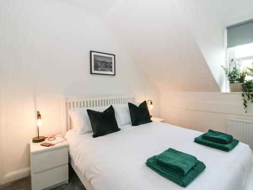 a bedroom with a white bed with two green towels on it at Tweed Bank in Lundin Links