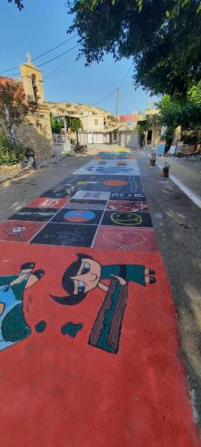 a street with a painting of a woman on the road at MATALA * LUX CAVE in Matala