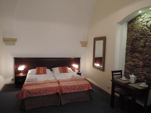 1 dormitorio con cama, mesa y espejo en Penzion U Císaře Zikmunda, en Znojmo