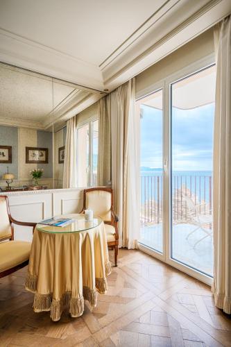 a living room with a table and a large window at Excelsior Palace Portofino Coast in Rapallo