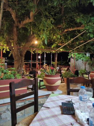 un restaurante con mesa, sillas y un árbol en Porto Sabatiki en Sampatiki