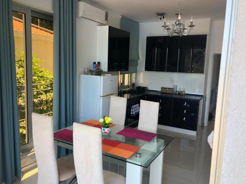 a kitchen with a glass table and white chairs at Apartment Galina in Tivat