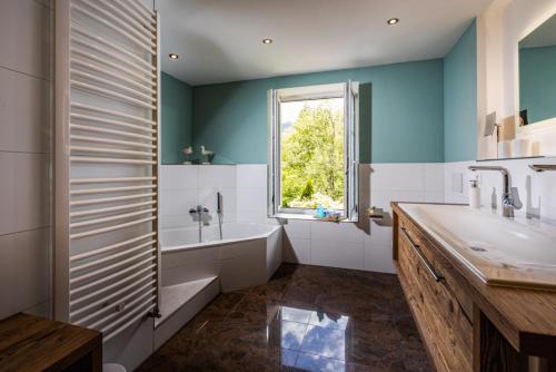 a bathroom with a tub and a sink and a window at Landurlaub Hinterbrandner in Marktschellenberg