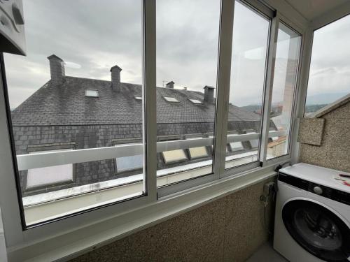 a washing machine in a room with two windows at Altamira in Caldas de Reis
