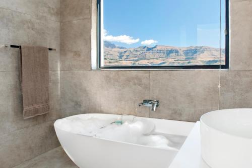 a white bath tub in a bathroom with a window at Eleven on Tumbleweed, Cathkin Estates in Champagne Valley