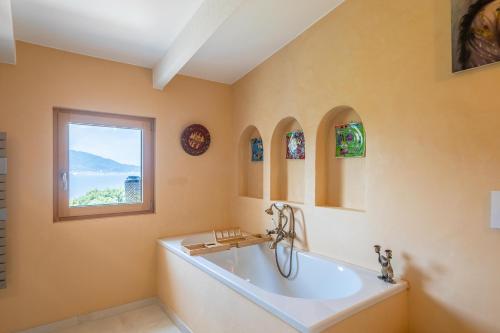 baño con bañera grande y ventana en U Tempu Persu, en Grosseto-Prugna