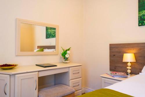 a bedroom with a desk with a mirror and a bed at The Limes Country Lodge Hotel & Admiral Restaurant in Solihull