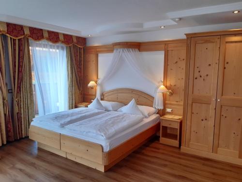 a bedroom with a large bed with a canopy at Garni Hotel Franca b&b in Selva di Val Gardena